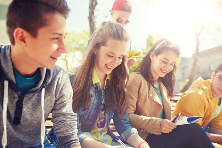 several teenagers sitting next to each other laughing while doing homework